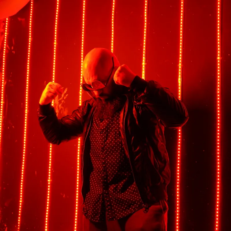 Superfoodman en pleine pose héroïque sous les néons rouges Superfoodman posant avec puissance devant un fond rouge lumineux, en costume sombre et lunettes de héros.